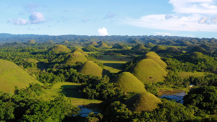 Panoramic view of Bohol’s Chocolate Hills and lush countryside under clear blue skies