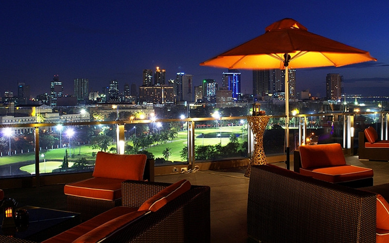Rooftop bar in Manila overlooking the city skyline at sunset with glowing lights