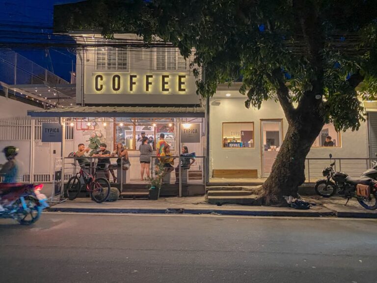 Barista pouring latte art in a cozy Philippine café with coffee beans on the counter