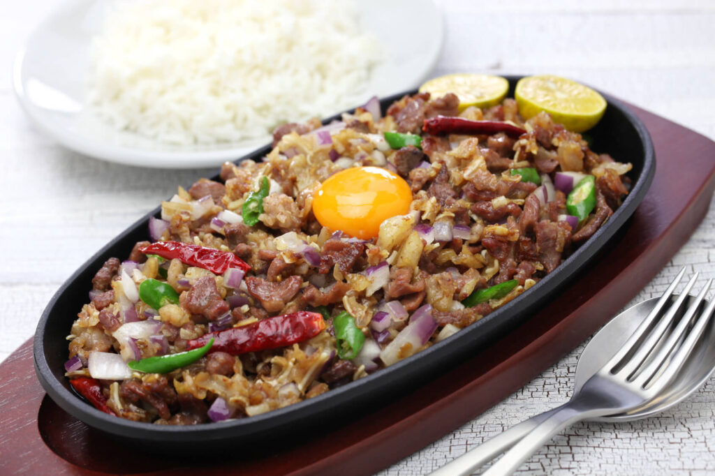 Sizzling plate of authentic Pampanga sisig topped with egg and chili