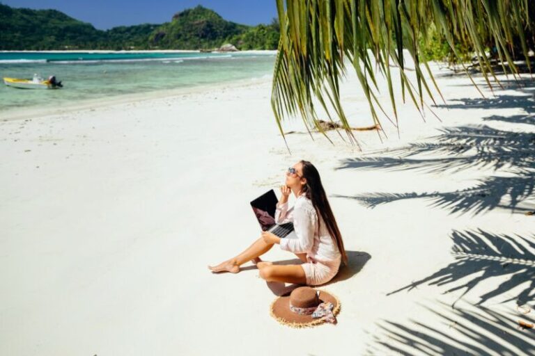 Remote worker using a laptop by the beach in the Philippines with palm trees in the background